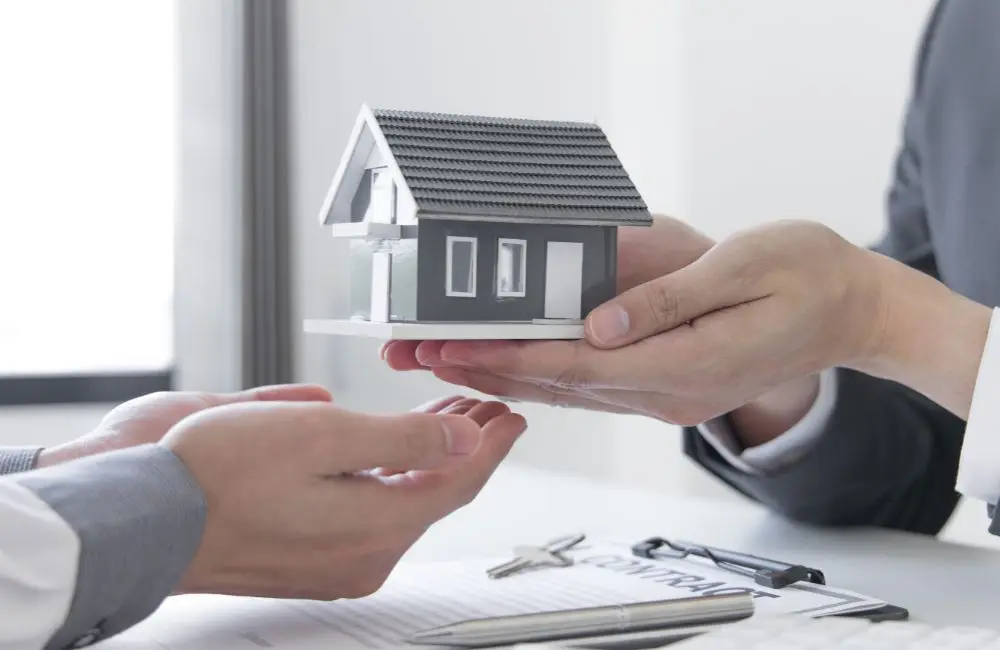 家の模型を手渡ししている画像