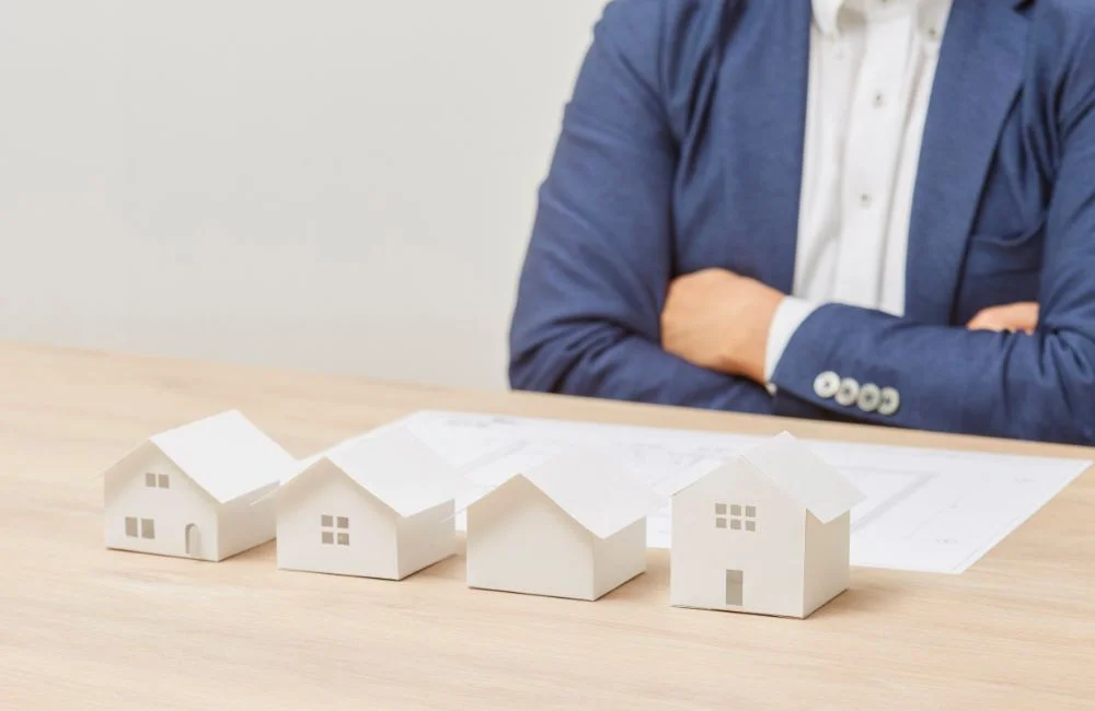 家の模型を並べて考えている男性